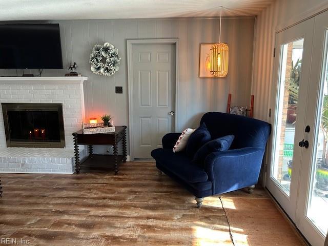 living room featuring a brick fireplace, french doors, and wood finished floors