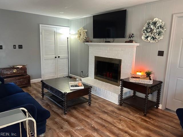 living area featuring a fireplace, baseboards, and wood finished floors