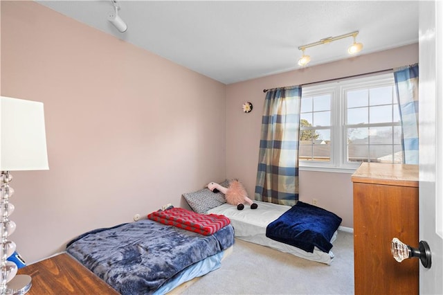 carpeted bedroom featuring rail lighting