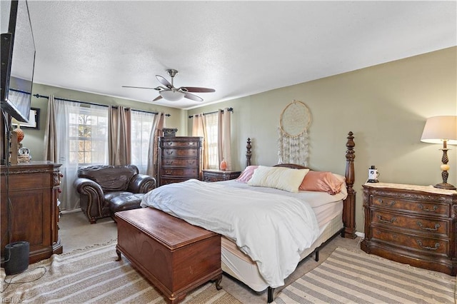 bedroom with ceiling fan, a textured ceiling, and light colored carpet