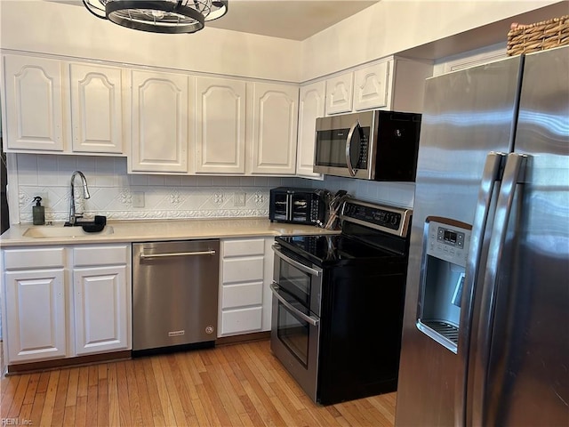 kitchen featuring a sink, white cabinetry, light countertops, appliances with stainless steel finishes, and light wood finished floors