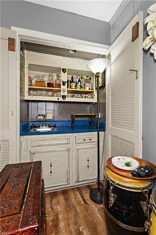 bar with dark wood-style floors, wet bar, and a sink