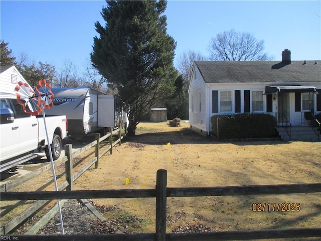 view of yard featuring driveway, fence, and an outdoor structure