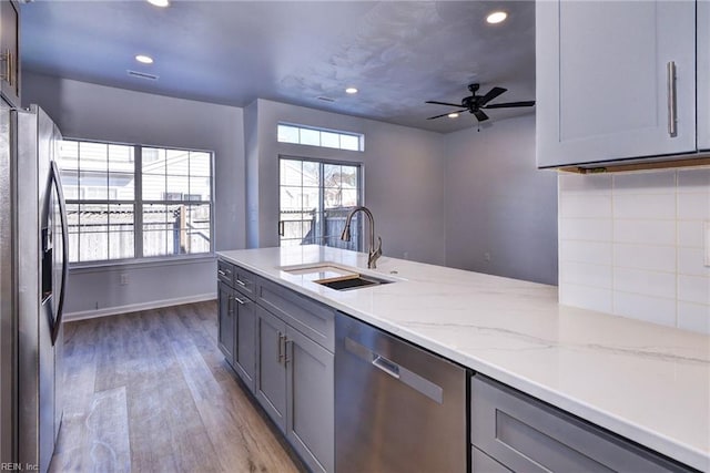 kitchen featuring a sink, appliances with stainless steel finishes, gray cabinets, and light stone countertops