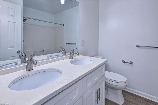 bathroom featuring double vanity, wood finished floors, a sink, and toilet