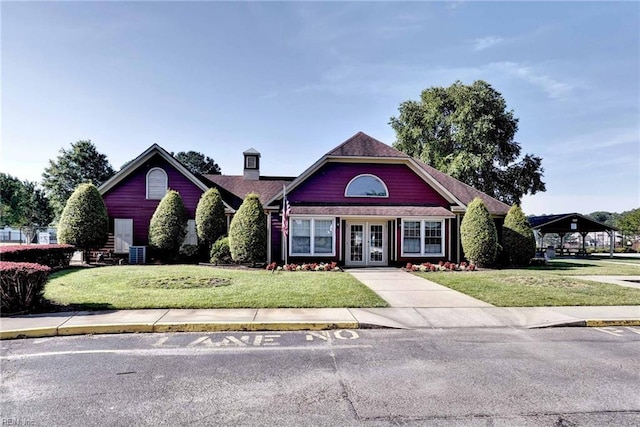 view of front of house with central AC, french doors, and a front lawn