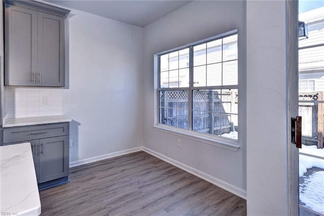 unfurnished dining area with wood finished floors and baseboards