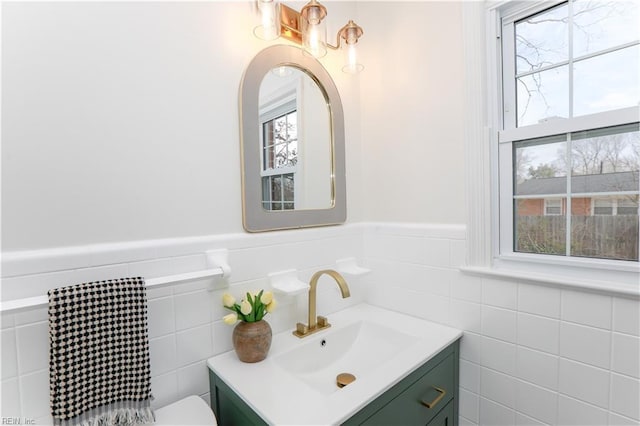 half bathroom with tile walls, wainscoting, and vanity