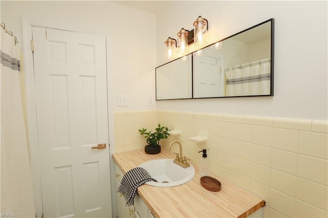 bathroom featuring a wainscoted wall, tile walls, and a sink