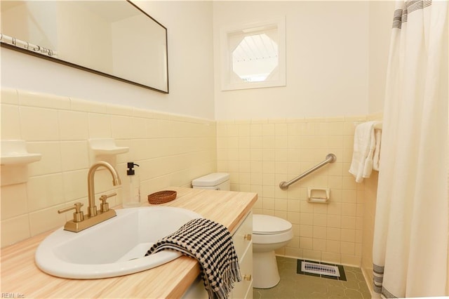 bathroom featuring tile patterned flooring, toilet, a sink, visible vents, and tile walls