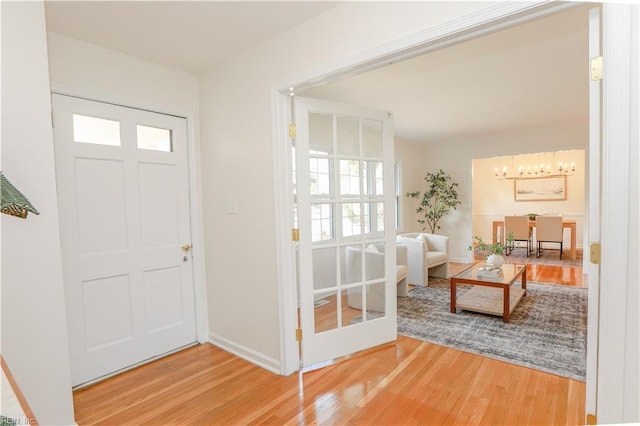 foyer featuring baseboards, a chandelier, and wood finished floors