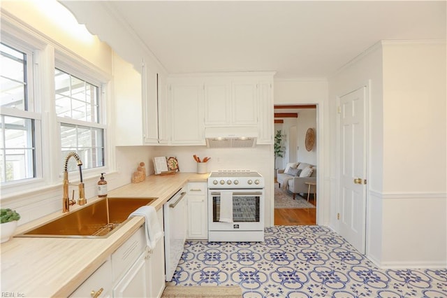 kitchen with light countertops, white appliances, a sink, and crown molding