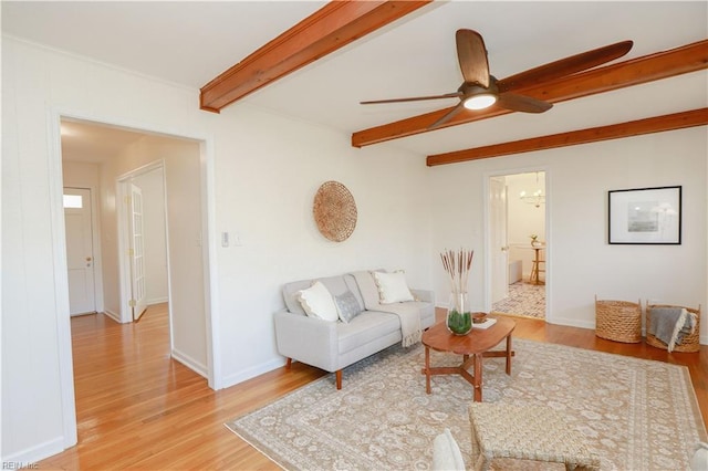 living room featuring ceiling fan, light wood-style flooring, beam ceiling, and baseboards