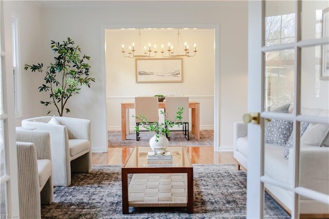 living area with an inviting chandelier, baseboards, and wood finished floors