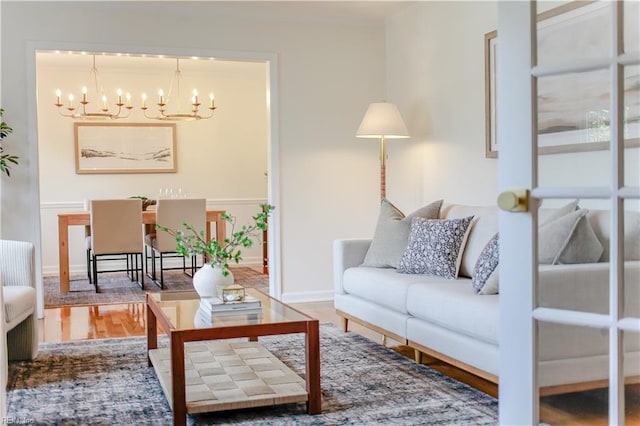 living room with baseboards, wood finished floors, and an inviting chandelier