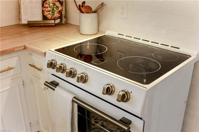 details featuring backsplash, white cabinetry, and electric range