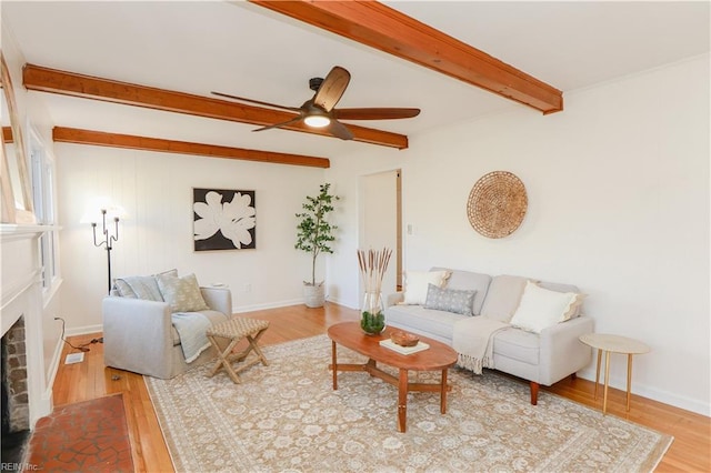 living room with baseboards, a fireplace, beamed ceiling, and light wood finished floors