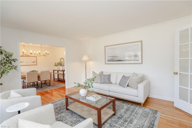 living room featuring baseboards, ornamental molding, wood finished floors, and an inviting chandelier