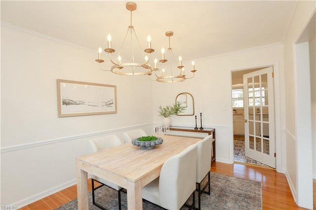 dining room featuring crown molding, a chandelier, wood finished floors, and wainscoting