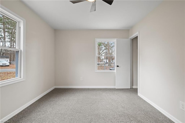 carpeted spare room featuring ceiling fan and baseboards