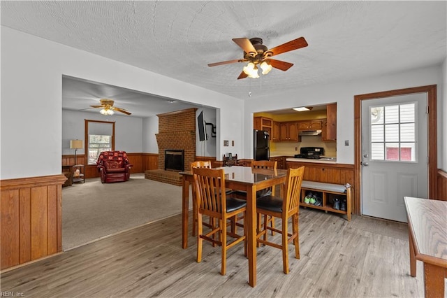 dining area with a ceiling fan, a wainscoted wall, plenty of natural light, and a textured ceiling