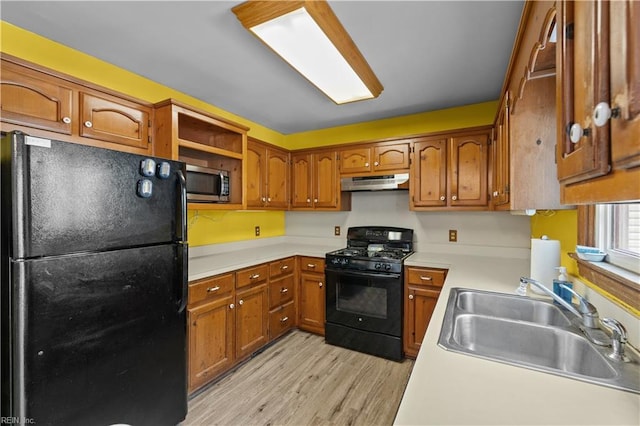 kitchen with black appliances, under cabinet range hood, brown cabinetry, and a sink