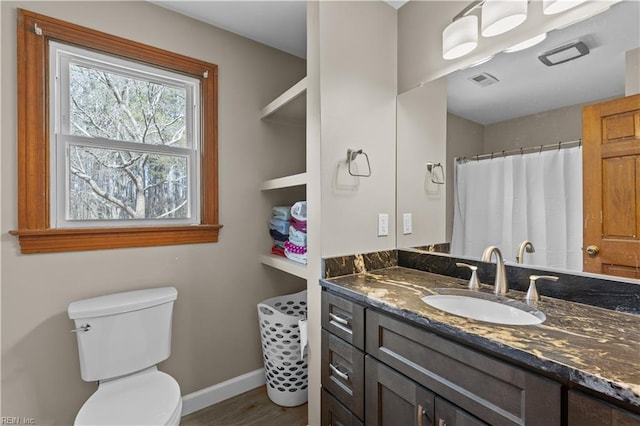 bathroom with toilet, vanity, visible vents, and baseboards