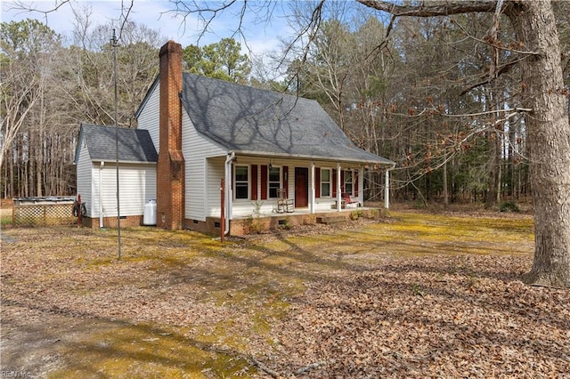 view of front of property with a shingled roof, a chimney, crawl space, an outdoor structure, and a porch