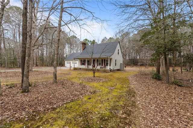 view of front of home featuring a porch, driveway, a chimney, and a garage