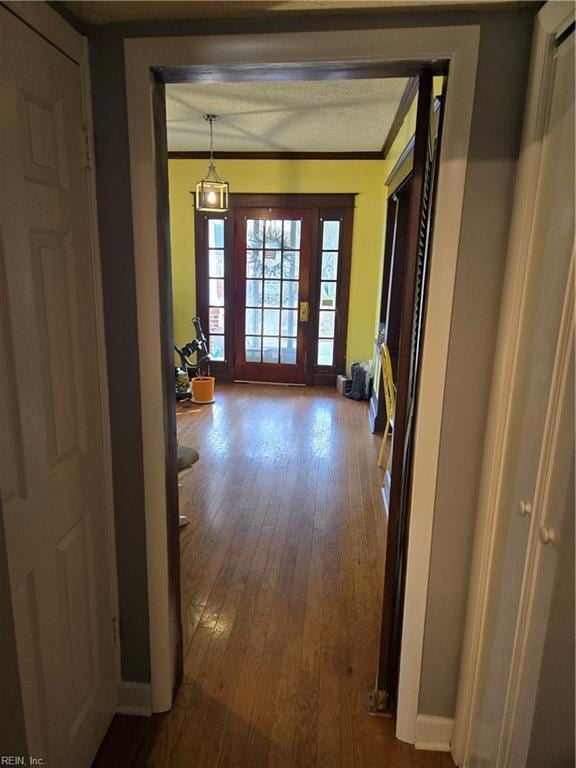 corridor with baseboards, wood finished floors, and crown molding