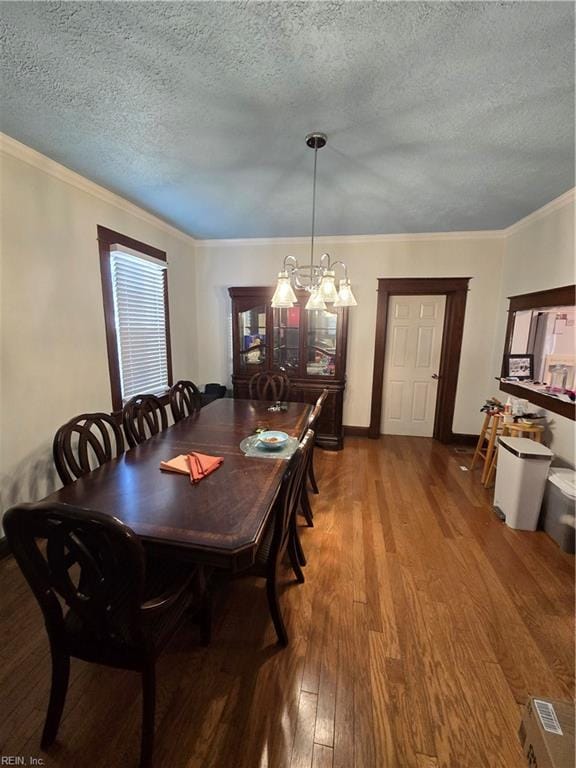 dining room with a textured ceiling, a chandelier, wood finished floors, baseboards, and ornamental molding