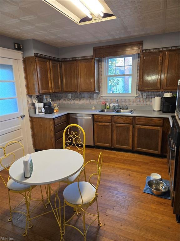 kitchen featuring light wood-type flooring, light countertops, a sink, and dishwasher