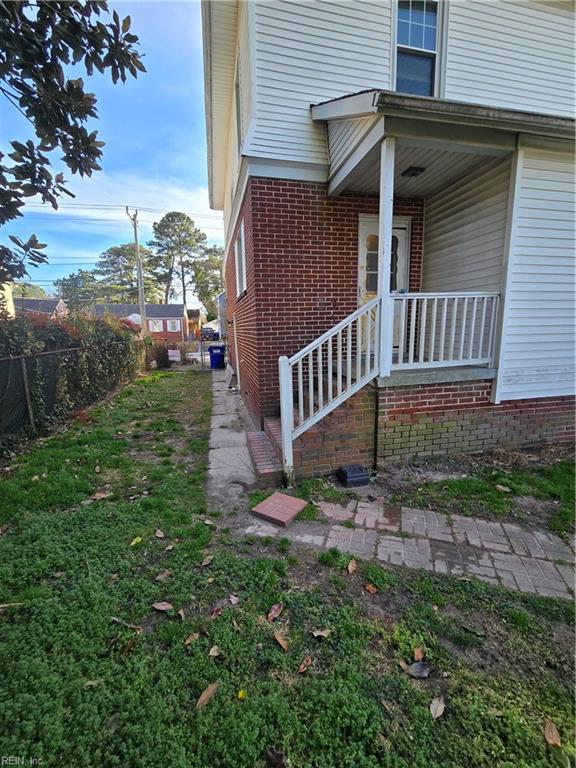 view of side of home featuring fence and brick siding