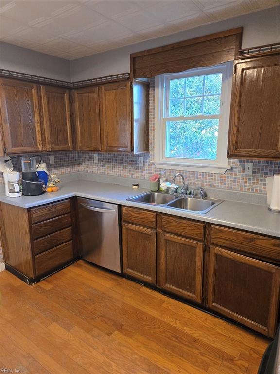 kitchen with a sink, light wood finished floors, light countertops, and stainless steel dishwasher