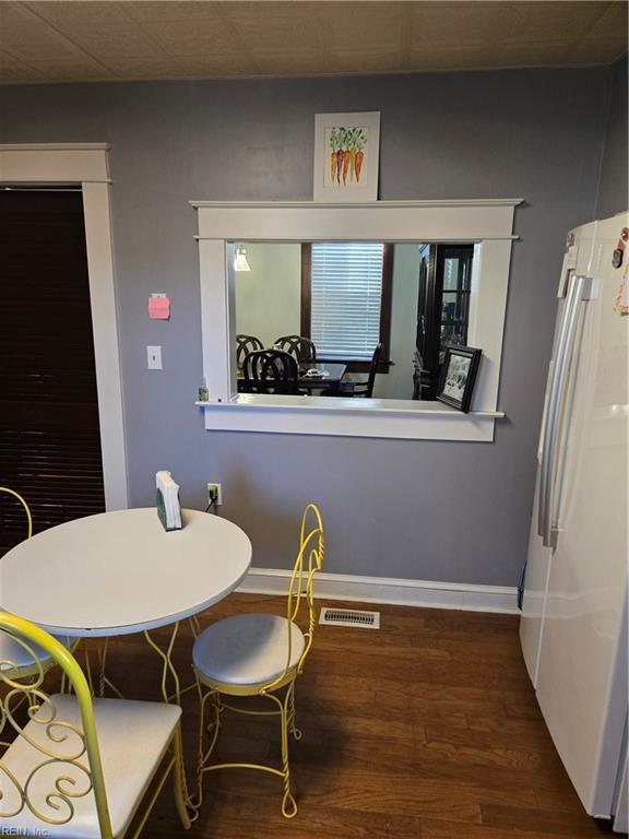 dining space with dark wood-type flooring, visible vents, and baseboards