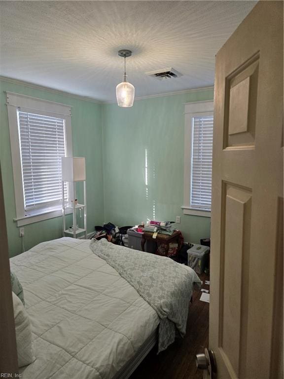 bedroom with visible vents, crown molding, and wood finished floors