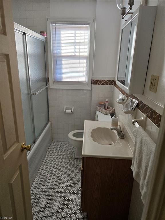 bathroom with enclosed tub / shower combo, toilet, tile walls, vanity, and tile patterned floors