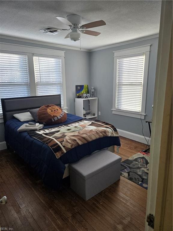 bedroom with dark wood-style floors, crown molding, visible vents, a textured ceiling, and baseboards