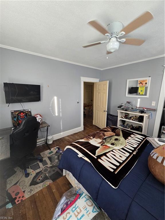 bedroom featuring dark wood-style floors, ornamental molding, a textured ceiling, and baseboards