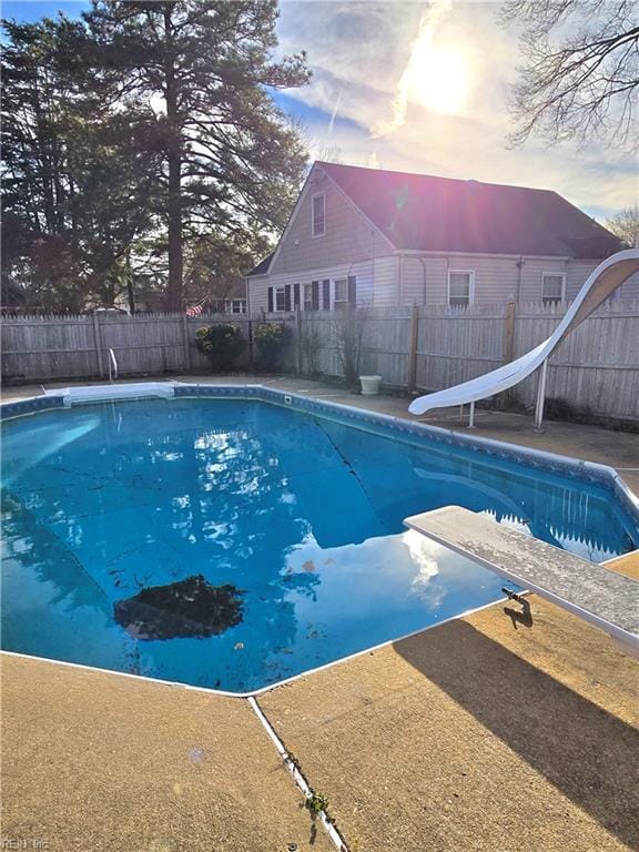 view of pool featuring a fenced backyard, a diving board, and a water slide