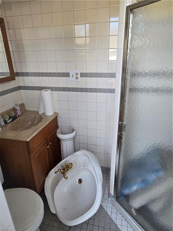 bathroom with tile patterned floors, a shower stall, tile walls, and vanity