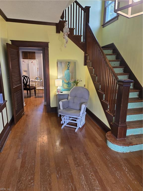 stairway featuring baseboards, wood finished floors, and crown molding