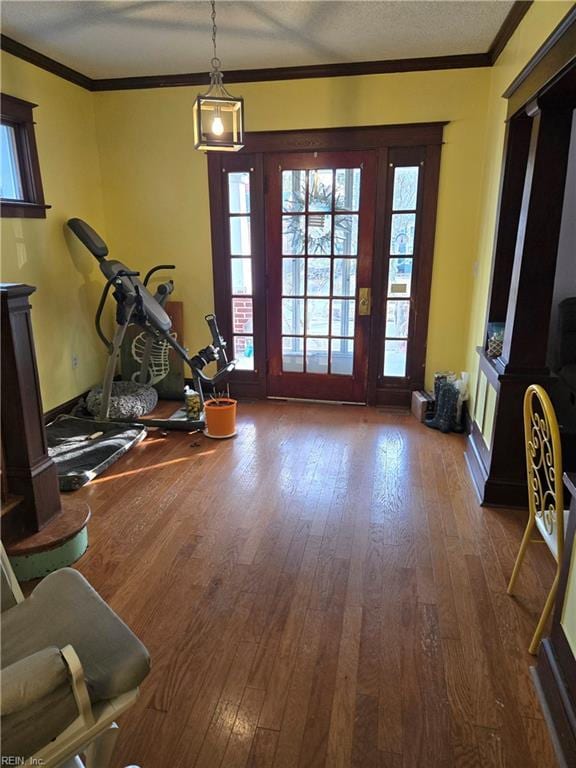 workout area with dark wood-type flooring, crown molding, and a textured ceiling