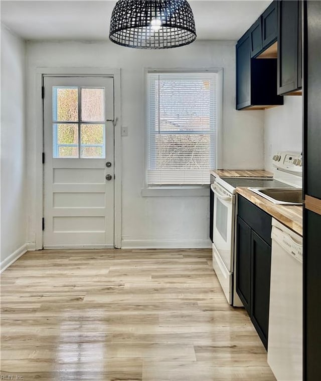 kitchen featuring light wood finished floors, wooden counters, white appliances, and a healthy amount of sunlight