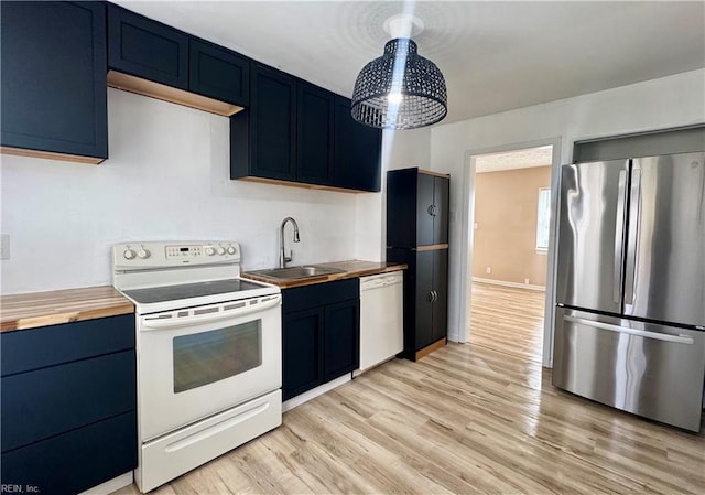 kitchen with butcher block countertops, white appliances, blue cabinets, and a sink