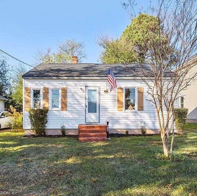 view of front of property featuring entry steps, a chimney, and a front yard