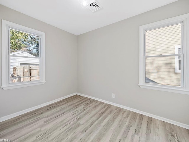 spare room featuring visible vents, light wood-style flooring, and baseboards