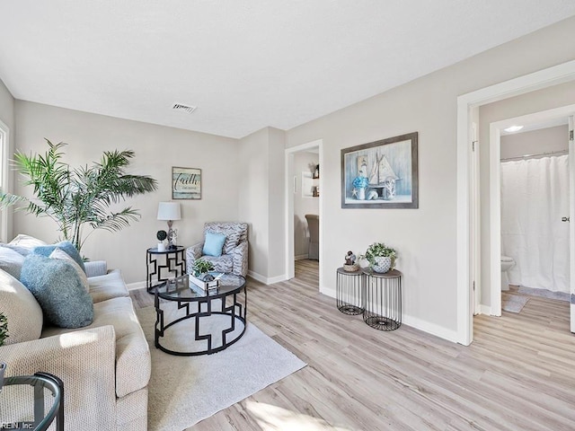 living area with baseboards, visible vents, and light wood-style floors