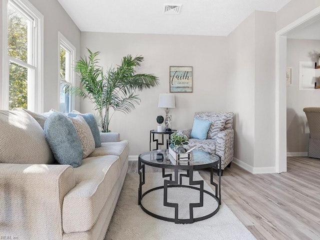 sitting room with light wood-style floors, visible vents, and baseboards