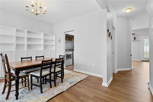 dining area with washer / clothes dryer, a notable chandelier, baseboards, and wood finished floors